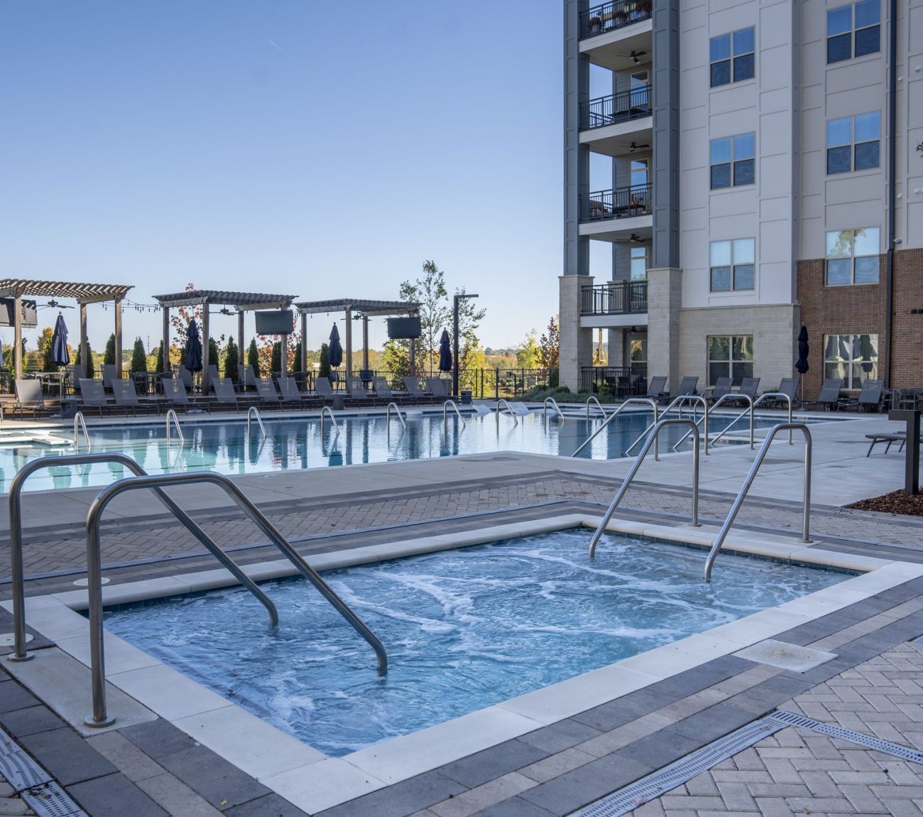 McEwen apartments outdoor jacuzzi with apartment building and pool behind at evening