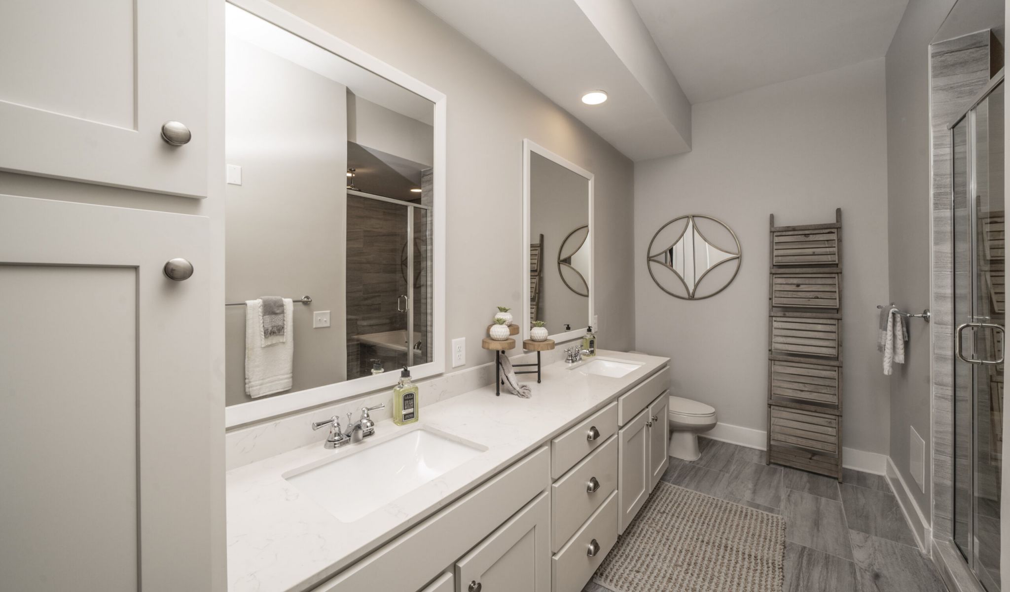 A beautiful apartment bedroom with double vanities and a glass enclosed shower